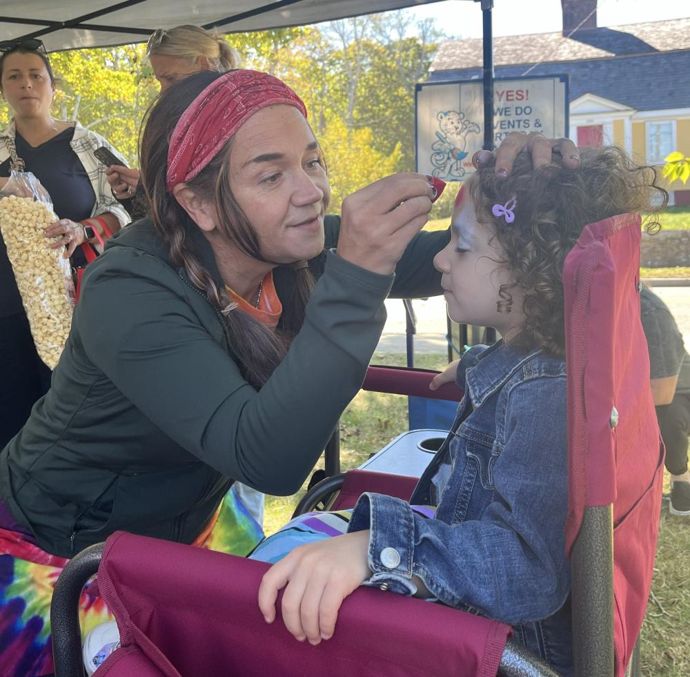 Beth Kelly from Art on the Spot paints a Spiderman design on a young girl's face. She has been facepainting for 15 years. Photos by Tanvi Kulkarni