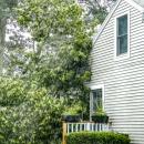 A view of the tree from the side, resting on the porch and the roof.a