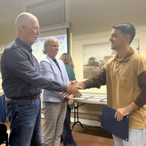 Special education teacher Cameron Decas shakes School Committee Chair Geoffrey Swett's hand. Photos by Tanvi Kulkarni